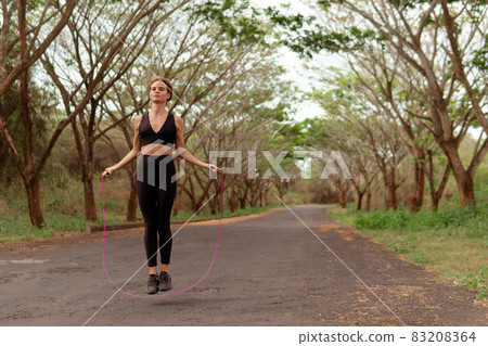 Woman in black sportwear jumping rope Woman in black sportwear jumping rope 83208364