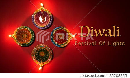 Happy Diwali - Clay Diya lamps lit during Dipavali, Hindu festival of lights celebration. Colorful traditional oil lamp diya on red .background 83208855