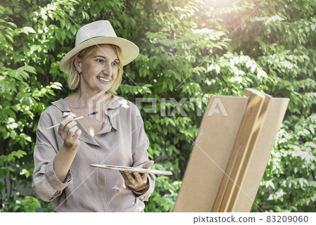 Portrait of happy senior caucasian artist mature woman paint with water color outdoor greenery class. Old creative gifted artist home school education. Healthy activity hobby lifestyle. 83209060