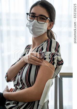 Young woman showing COVID-19 vaccine bandage merrily 83210225