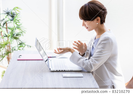A smiling business woman making a video call A smiling business woman making a video call 83210270