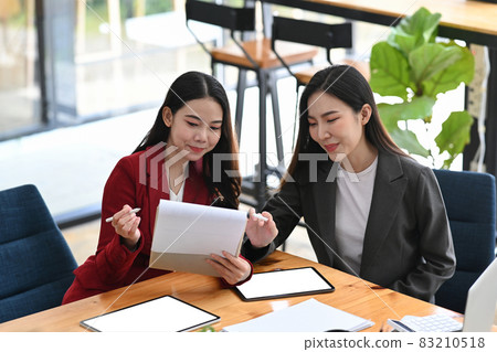 Two businesswoman analyzing financial reports together at modern workplace. Two businesswoman analyzing financial reports together at modern workplace. 83210518