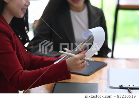 Businesswoman checking financial document while sitting with her colleague in office. 83210519