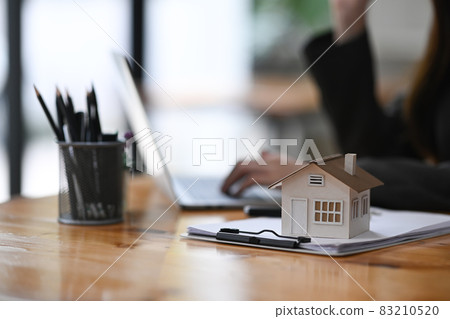 House model and clipboard on wooden table. Mortgage and real estate investment. 83210520