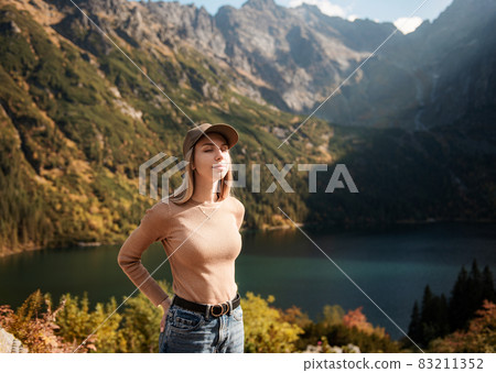 Wanderlust and travel concept. Stylish traveler girl in cap looking in front of mountain  83211352