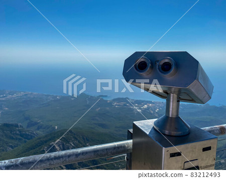 stationary binoculars on the viewing platform aimed at the mountains 83212493