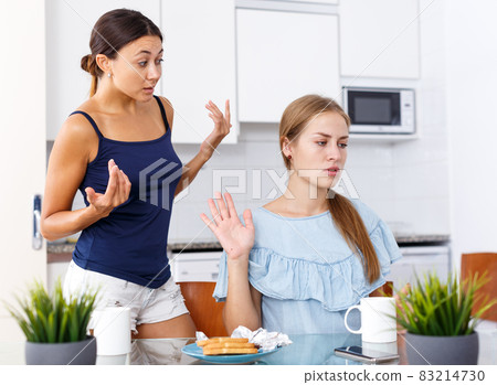 Upset young women friends quarrelling and drinking tea at home 83214730