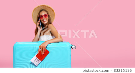 Glad Traveler girl holds passport, ticket, money with suitcase calls taxi to airport. Travel concept 83215156