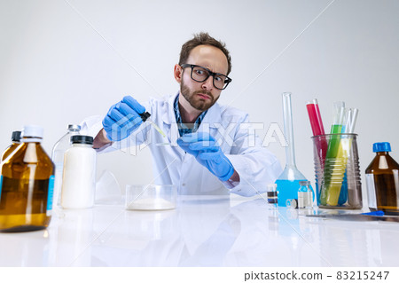 Portrait of young scientist, chemist or doctor conducts chemical research at pharmaceutical lab. Concept of chemistry, medicine. 83215247