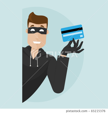 The thief peeks around the corner and holds a stolen credit card in his hand. The thief peeks around the corner and holds a stolen credit card in his hand. 83215376