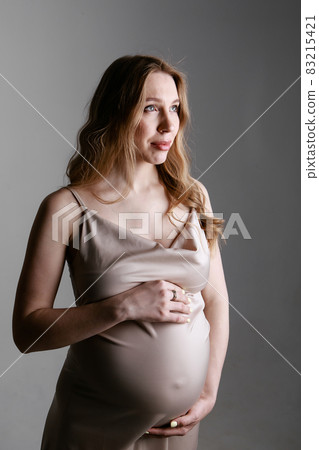 caucasian pregnant woman stroking her belly on white background. Copy space. The concept of healthy digestion, lifestyle, IVF 83215421