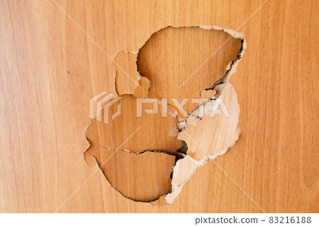 The concept of displaying aggression, damage to furniture. A hole in a wooden wall from a strong blow. The concept of displaying aggression, damage to furniture. A hole in a wooden wall from a strong blow. 83216188