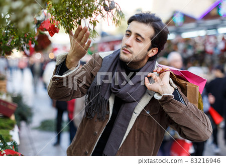 Smiling young man with Christmas toys at fair outside 83216946