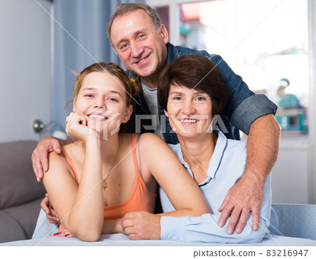Portrait of marrieds with their adult daughter at the table 83216947