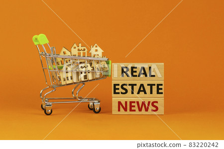 Real estate news symbol. Wooden blocks, words 'Real estate news' on beautiful orange background. Shopping cart with miniature wooden houses. Business, Real estate news concept. Copy space. 83220242