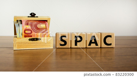 SPAC, special purpose acquisition company symbol. Wooden cubes with word 'SPAC' on beautiful white background, copy space. Euro bills. Business and SPAC, special purpose acquisition company concept. 83220300