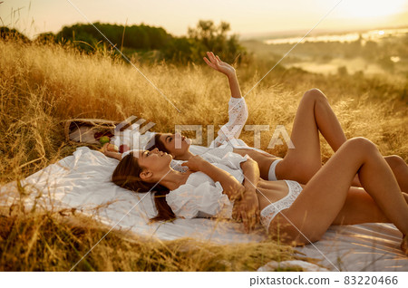 Two women in lingerie lying on blanket in field Two women in lingerie lying on blanket in field 83220466