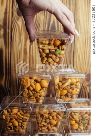 Close-up of a beer snack. Hazelnuts, cashews and peanuts with different flavors in transparent packaging. Snacks go with alcohol. Takeaway food. Concept Close-up of a beer snack. Hazelnuts, cashews and peanuts with different flavors in transparent packaging. Snacks go with alcohol. Takeaway food. Concept 83222605