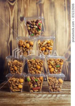 Close-up of a beer snack. Hazelnuts, cashews and peanuts with different flavors in transparent packaging. Snacks go with alcohol. Takeaway food. Concept Close-up of a beer snack. Hazelnuts, cashews and peanuts with different flavors in transparent packaging. Snacks go with alcohol. Takeaway food. Concept 83222606