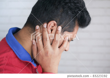 young man having ear pain touching his painful ear , young man having ear pain touching his painful ear , 83223192