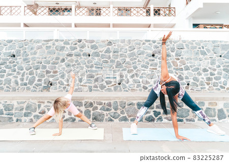 Healthy happy family mom and daughter doing stretching exercises on seaside Healthy happy family mom and daughter doing stretching exercises on seaside 83225287