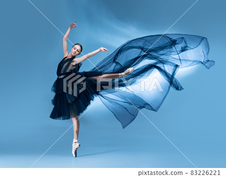 Young and graceful ballet dancer in black stage outfit, dress isolated on white blue studio background in neon light. Young and graceful ballet dancer in black stage outfit, dress isolated on white blue studio background in neon light. 83226221