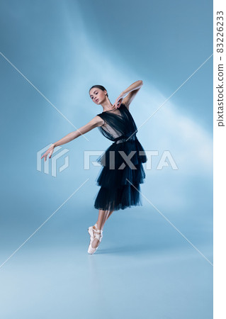 Young and graceful ballet dancer in black stage outfit, dress isolated on white blue studio background in neon light. 83226233
