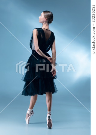 Young and graceful ballet dancer in black stage outfit, dress isolated on white blue studio background in neon light. 83226252
