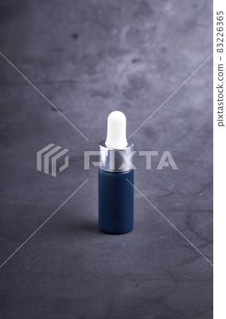 Blue dropper bottle on a dark background. Beauty care concept 83226365