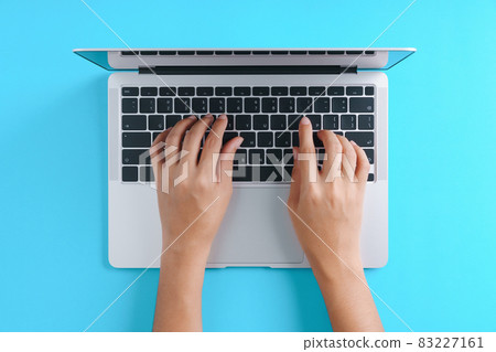 hand using laptop computer on blue background top view hand using laptop computer on blue background top view 83227161