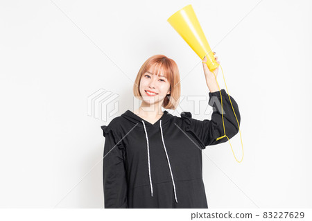 Young woman making a cheering gesture in front of a white background Young woman making a cheering gesture in front of a white background 83227629