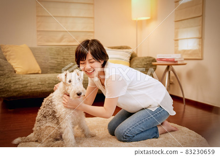 Young woman relaxing with her dog in the living room 83230659