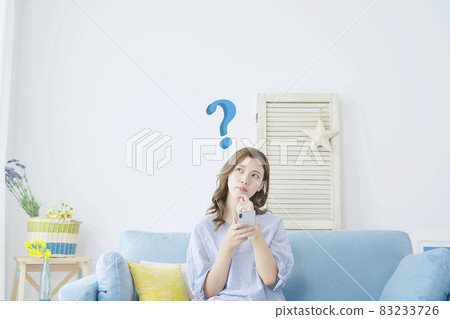 考慮一個在房間裡使用智能手機的女人 83233726