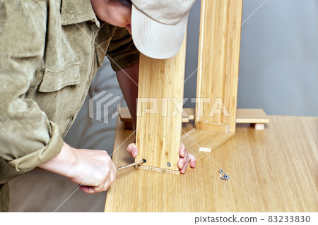Flat pack furniture assembly by handyman with screwdriver. Flat pack furniture assembly by handyman with screwdriver. 83233830