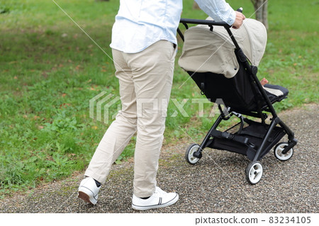 Daddy taking a walk with a 0 year old baby in a stroller 83234105
