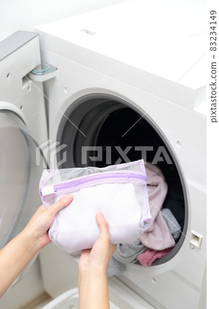 Hands of a housewife who puts it in the laundry net and does fashionable clothes washing 83234149
