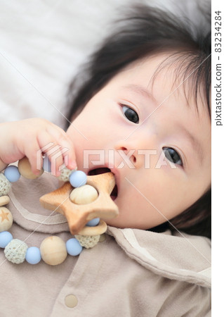 6 month old baby girl biting a tooth-hardening toy 6 month old baby girl biting a tooth-hardening toy 83234284