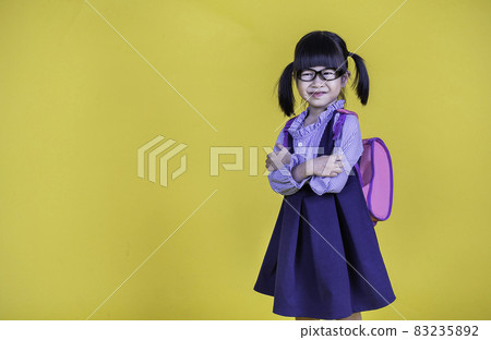 Portrait of young happy little cute asian girl in school uniform isolated on yellow background with copy space. Education for toddler or preschool, childhood lifestyle back to school concept Portrait of young happy little cute asian girl in school uniform isolated on yellow background with copy space. Education for toddler or preschool, childhood lifestyle back to school concept 83235892