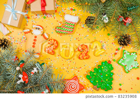 Christmas of gingerbread cookies 2022 in different shapes on yellow surface. Flat lay, top view. Christmas of gingerbread cookies 2022 in different shapes on yellow surface. Flat lay, top view. 83235908