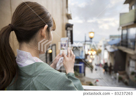 A young woman taking a picture of Ikaho's stone steps with her smartphone in the evening 83237263