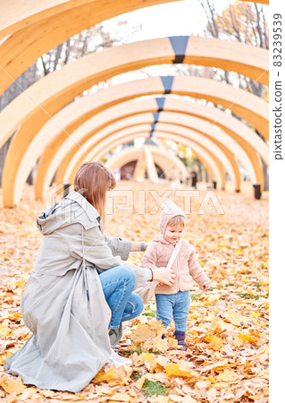 Portraits of a cute 1 year old baby girl and her young mother. Walking in Yellow Autumn Park. Leaf fall and yellow leaves. sunny day 83239539
