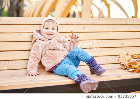 Yellow Autumn Park. Leaf fall and yellow leaves. Portraits of a cute 1 year old baby girl. sunny day. 83239554