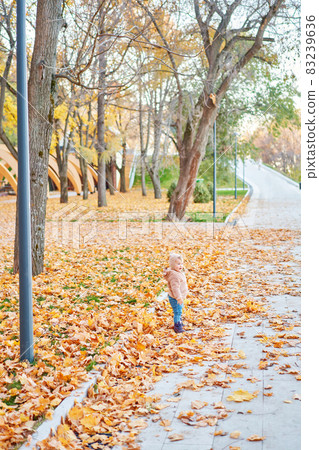 Yellow Autumn Park. Leaf fall and yellow leaves. Portraits of a cute 1 year old baby girl. sunny day. 83239636