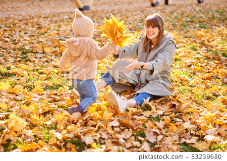 Portraits of a cute 1 year old baby girl and her young mother. Walking in Yellow Autumn Park. Leaf fall and yellow leaves. sunny day 83239680