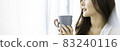 Portrait of young beautiful asian woman hands holding coffee cup morning spring time in white bedroom. Happy cheerful relaxing in summer. Korean makeup wakeup university asia lifestyle concept. 83240116