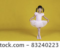 Portrait of little asian child girl dreams of becoming ballerina in a pink tutu skirt isolated on yellow background. Happy young girl practise her dance. Education childhood toddler lifestyle concept 83240223