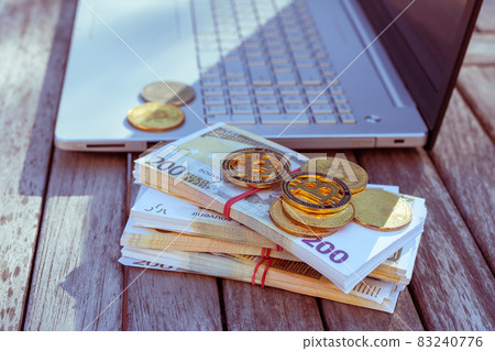 There is a laptop and bitcoins on the table. There is a laptop and bitcoins on the table. 83240776