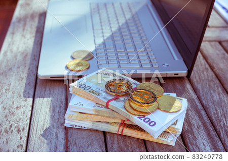 There is a laptop and bitcoins on the table. There is a laptop and bitcoins on the table. 83240778