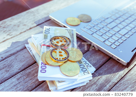 There is a laptop and bitcoins on the table. There is a laptop and bitcoins on the table. 83240779
