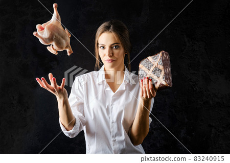 Woman tossing up fresg chicken with one hand and holding meat pie with another 83240915